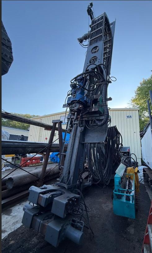 Upward view of a Casagrande M6A-1 micropile drilling rig, showing its tall mast, hydraulic system, and controls.